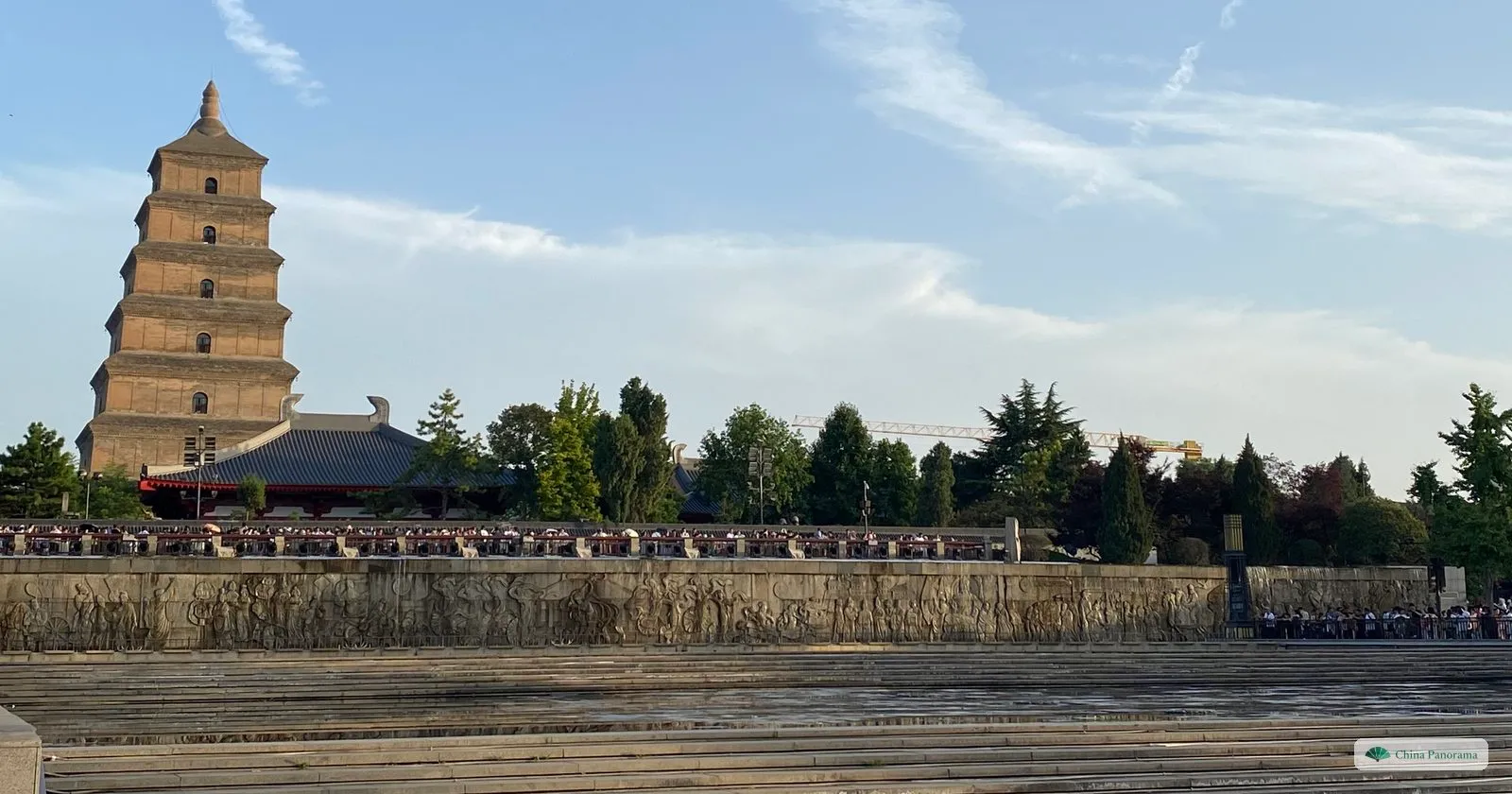 The Giant Wild Goose Pagoda, a seven-storey square brick tower, in evening light behind the stone reliefs and the empty stepped basin of the North Square fountain