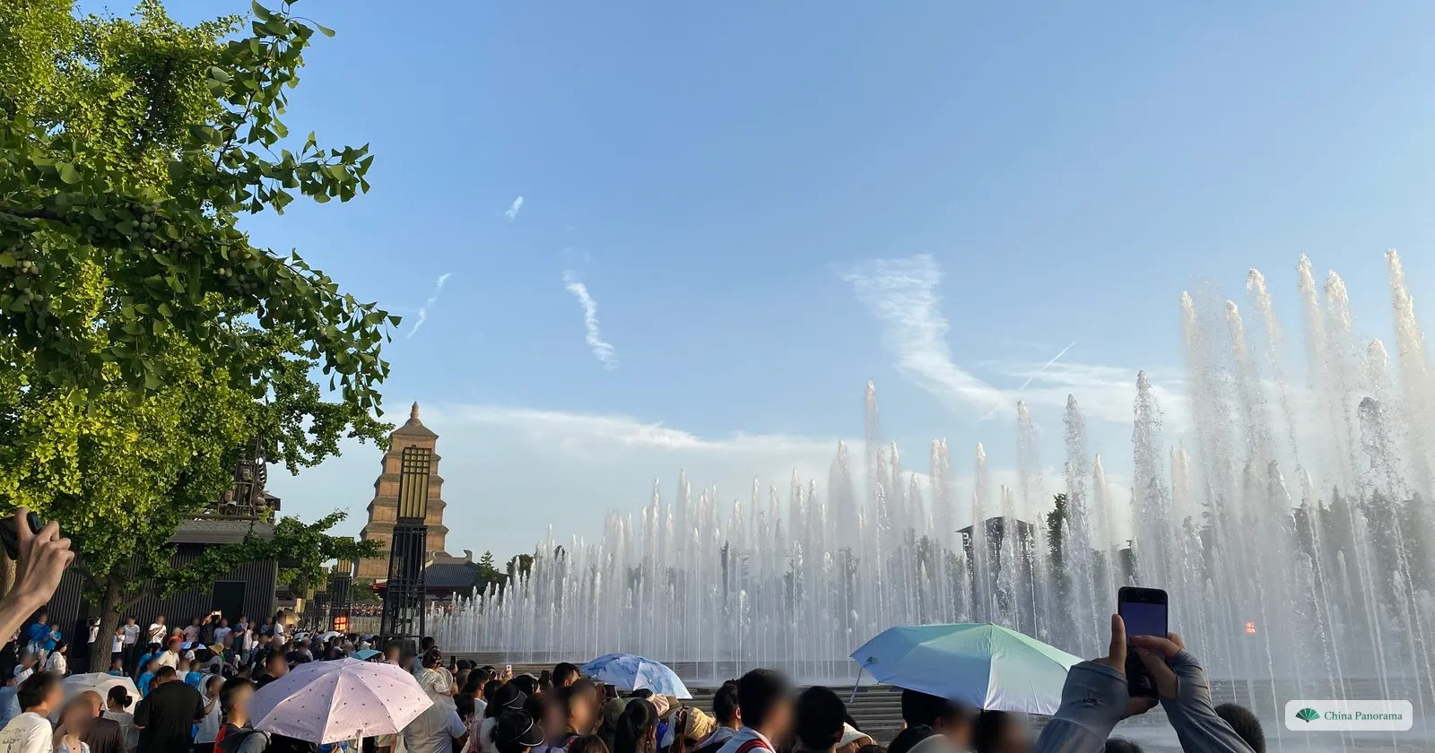 Rows of fountain jets playing on the North Square with the Giant Wild Goose Pagoda behind, and a crowd under parasols watching from the edge of the basin