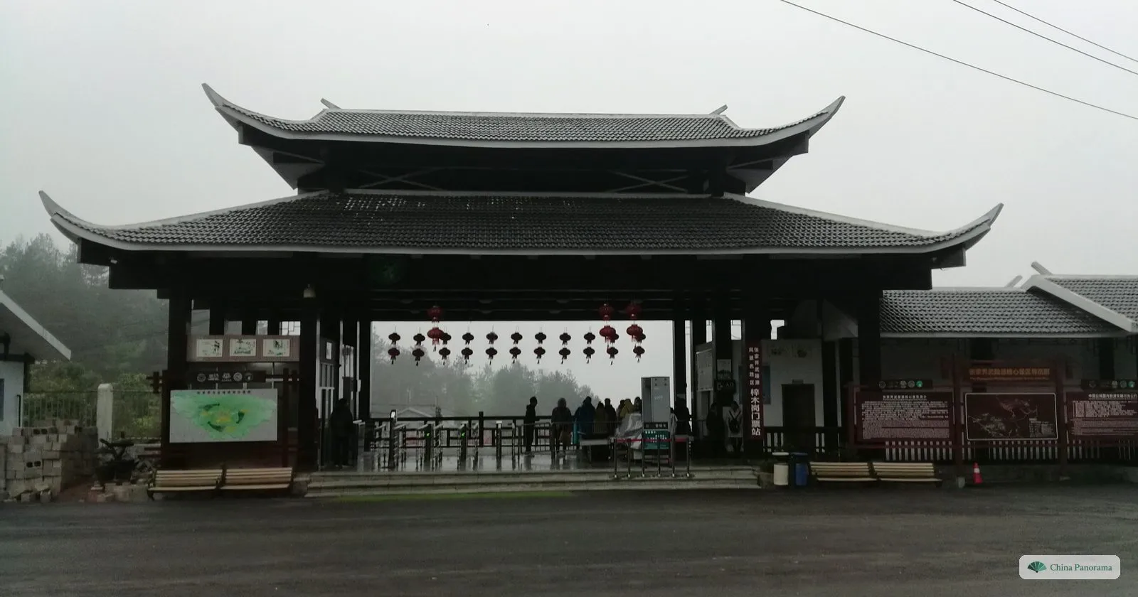 The Zimugang ticket station: a wide gatehouse with a double roof and a row of red lanterns, turnstiles underneath, a map board on the left and cloud behind